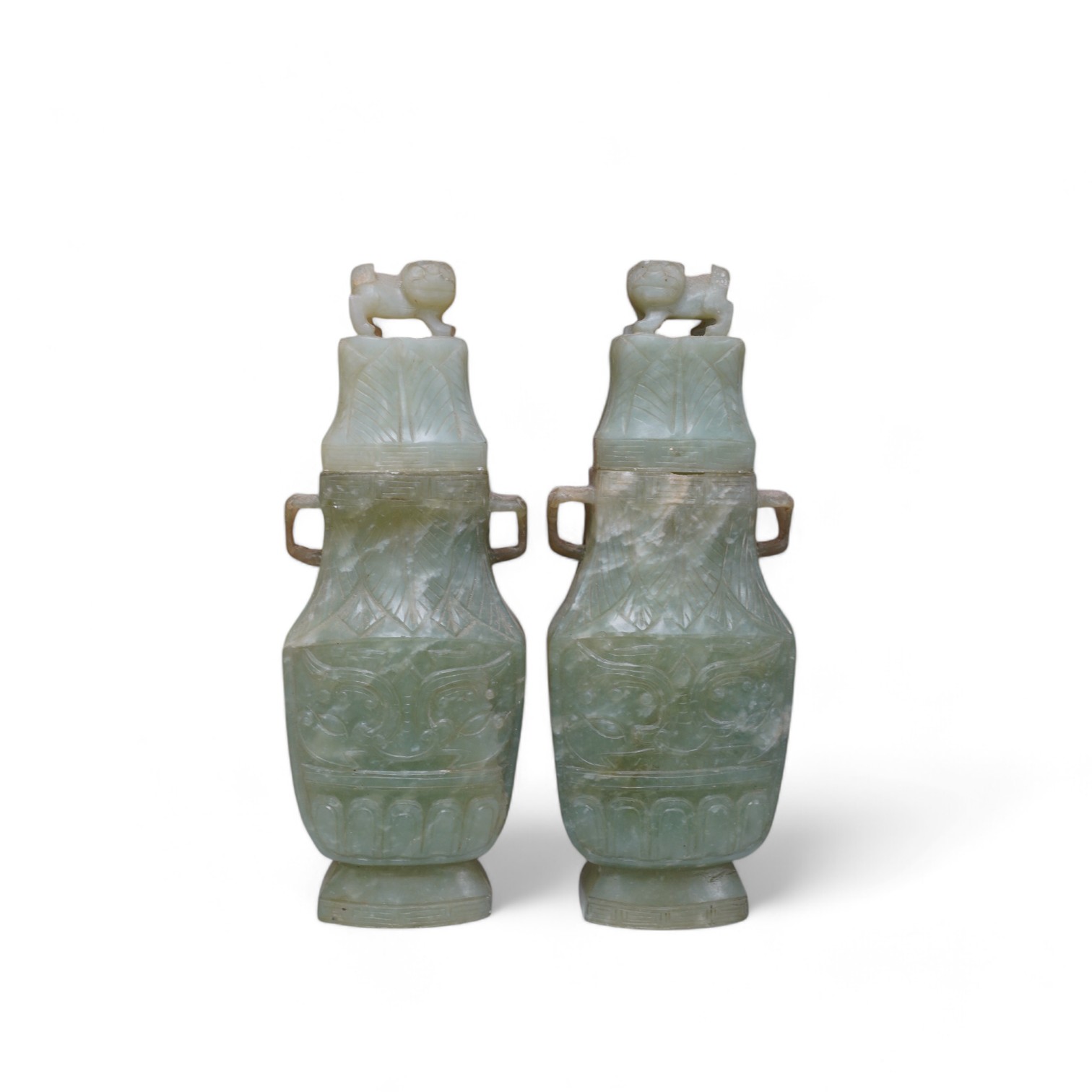 A pair of Chinese carved green quartz vases and covers, 21cm. Condition - fair, natural crack to body of one vase, chips to edges of both